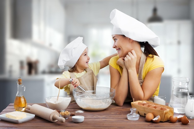 幸せな若い母親と子供が自家製の料理を準備しています