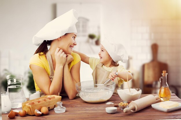 幸せな若い母親と子供が自家製の料理を準備しています