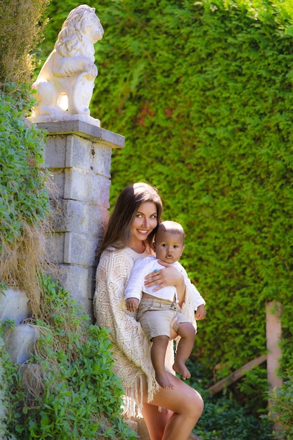 Happy young mother diverse parents with baby in summer yard overjoyed mother with small baby child