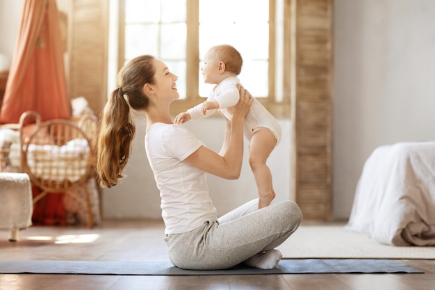 自宅で幼児と一緒に運動する幸せな若い母親