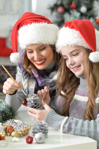 Felice giovane madre e sua figlia con i cappelli di babbo natale che si preparano per il natale