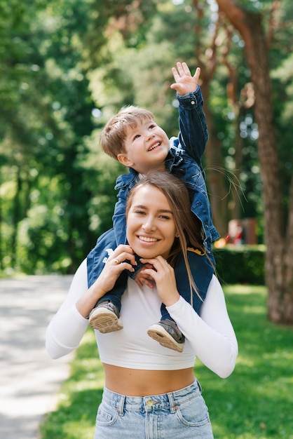 Happy young mother holds a cute baby in her arms the family is having fun together on the street on a sunny summer day in the park