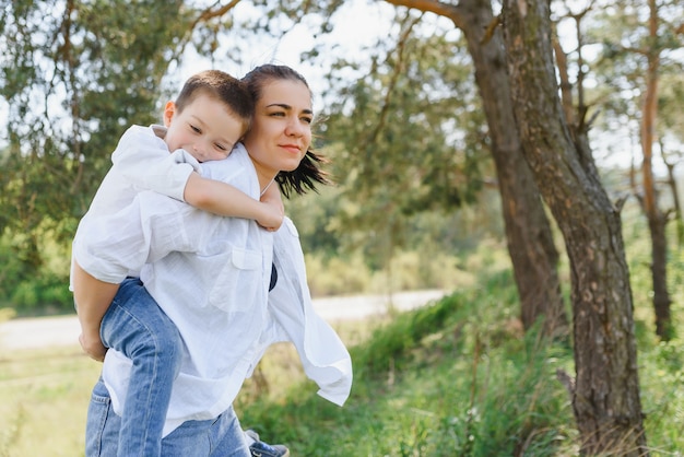 Happy young mother is playing with her baby in a park on a green lawn