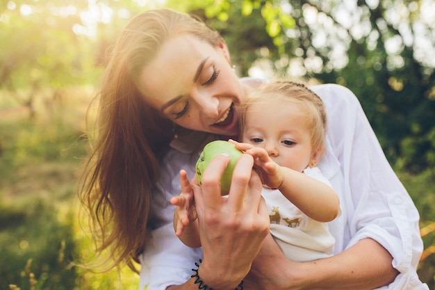 Photo happy young mother and lovely daughter holding apple