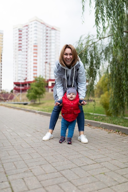 Счастливая молодая мать гуляет со своим маленьким сыном в парке