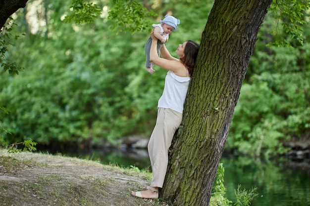 Happy young mother with little boy play outdoors during walking