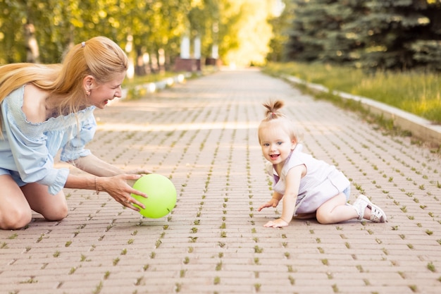 Happy young mother with little cute baby in summer park