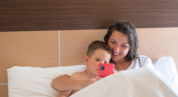 Happy young mother with little son using smart phone together