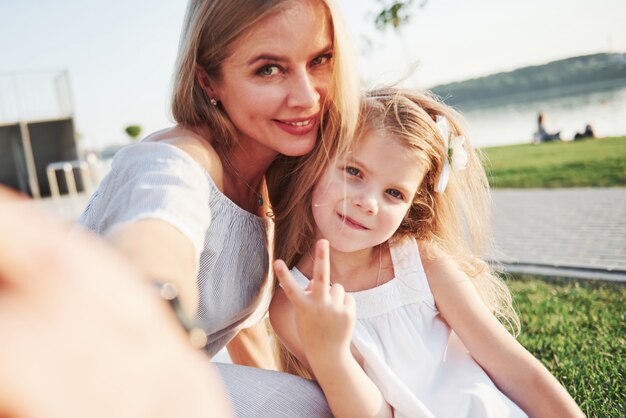 Happy young mother with a playful daughter in a park near the water