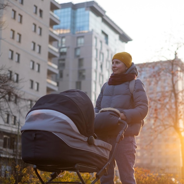 Happy young mother with pram during the walk