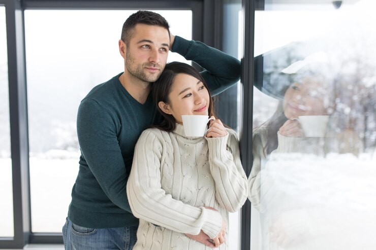 Photo 自宅で寒い冬の日に窓際で朝のコーヒーを楽しんでいる幸せな若い多民族カップル