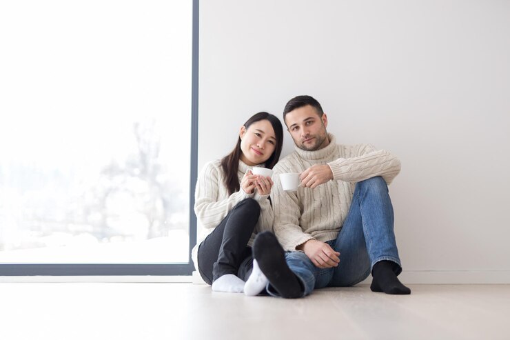 Photo happy young multiethnic couple enjoying morning coffee by the window on cold winter day at home