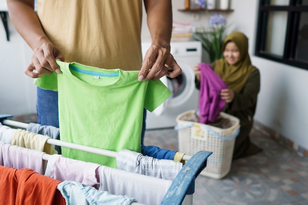 幸せな若いイスラム教徒の女性と彼女の夫は家で一緒に洗濯をしています
