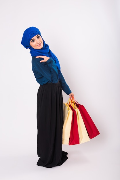 Счастливая молодая мусульманская женщина с хозяйственной сумкой на белой предпосылке.