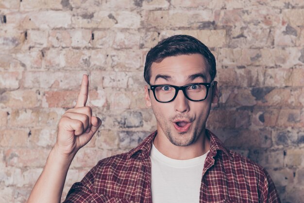 Happy young nerd guy raising his finger having an idea