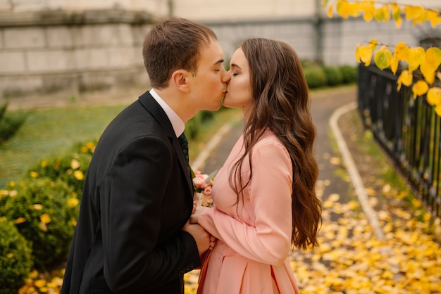 Happy young newly married wedding couple on walk in golden yellow fall autumn park near vintage atmosphere gothic cathedral.