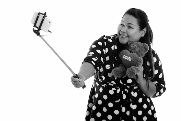 Happy young overweight asian woman holding teddy bear