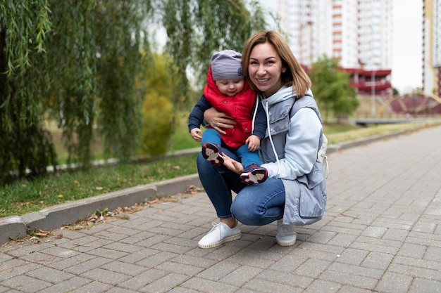 Happy young parent squatted with her little son in the park