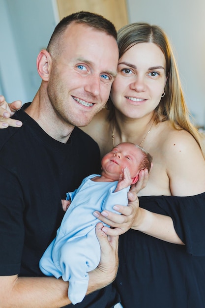 Photo happy young parents hold their newborn son in their arms smiling happy couple hugging their newborn baby one day for a newborn baby