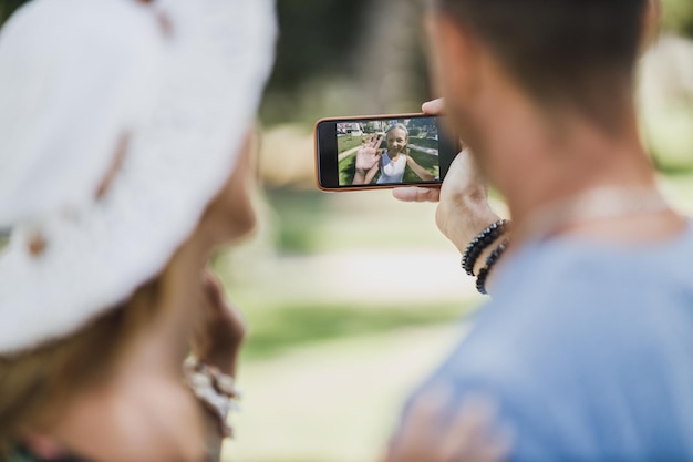 Foto giovani genitori felici che fanno una videochiamata con la loro figlia carina tramite smartphone mentre si godono una giornata estiva nel parco.