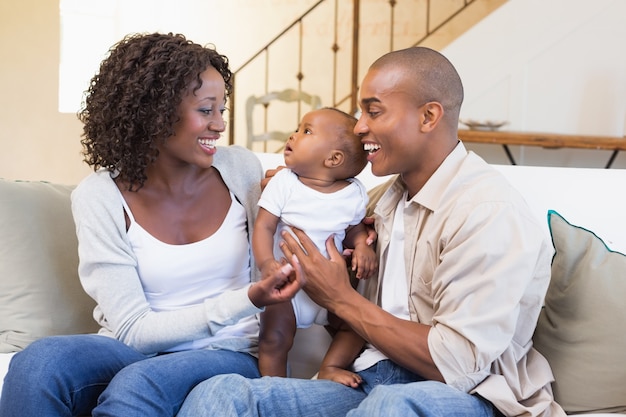 Happy young parents spending time with baby on the couch