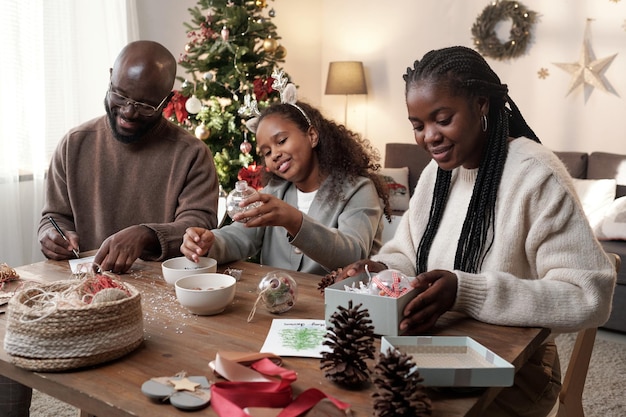 Happy young parents and their cute daughter preparing presents