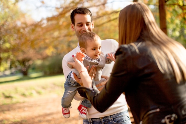 Happy young parents with baby boy in autumn park