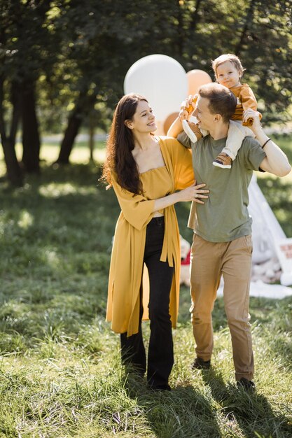 Happy young parents with lovely son playing near teepee tent