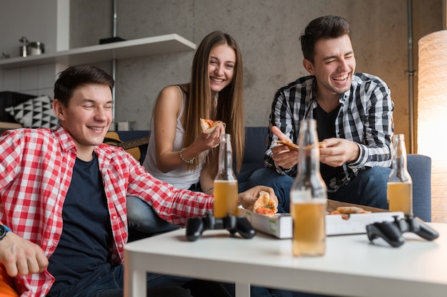 Happy young people eating pizza, drinking beer, having fun