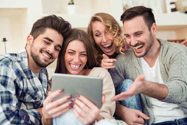 Счастливые молодые люди, проводящие время вместе, с помощью планшета.