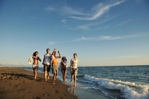 happy young people group have fun white running and jumping on beacz at sunset time