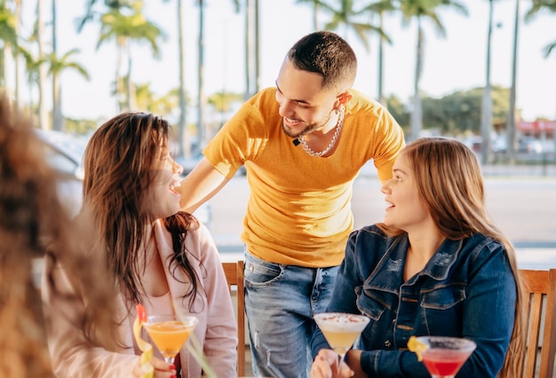 Happy young people having fun and drinking cocktails at outdoor bar table