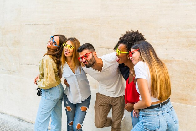 Happy young people holding fake eyeglasses having fun photo and carnival funny accessories