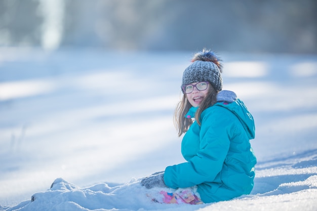 雪で遊んで暖かい服を着た幸せな若いプレティーンの女の子。