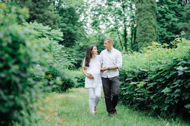 Happy and young pregnant couple hugging in nature