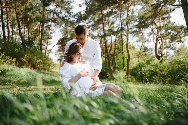 Happy and young pregnant couple hugging in nature