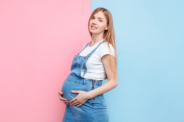 Happy young pregnant girl strokes her belly with her hands