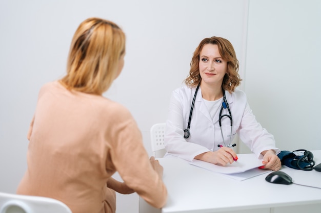 Happy young pregnant woman with blonde hair visiting doctor in prenatal clinic