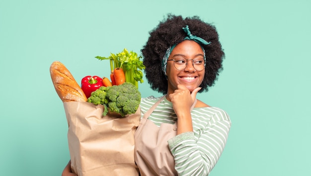 Happy young pretty afro woman holding a vegetables bag