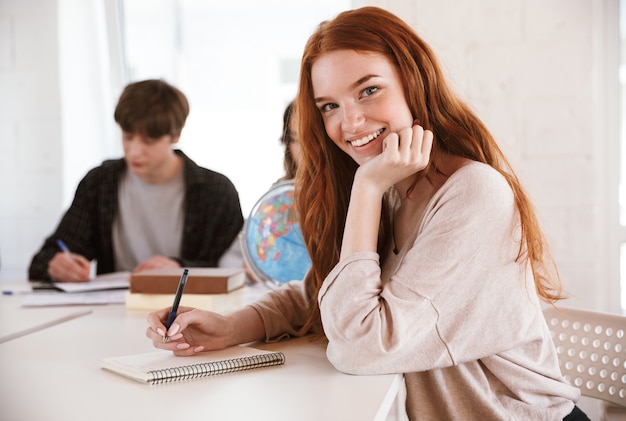 Happy young redhead lady writing notes