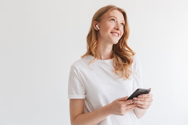 Photo happy young redhead woman listening music with earphones by mobile phone.