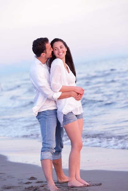 愛の幸せな若いロマンチックなカップルは、美しい夏の日に美しいビーチで楽しんでいます