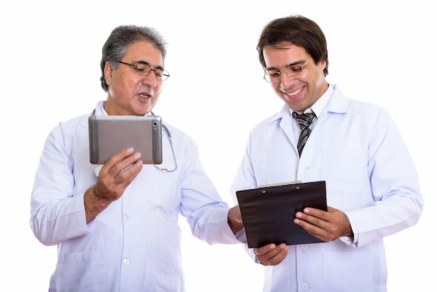 happy young and senior Persian man doctor smiling and holding digital tablet and clipboard