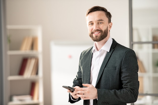 Foto felice giovane manager sorridente o agente con lo smartphone