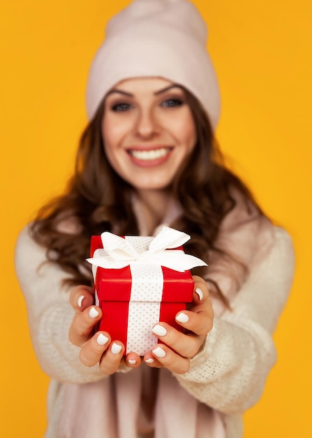 Happy young smiling woman holding and holding red gift box in fr