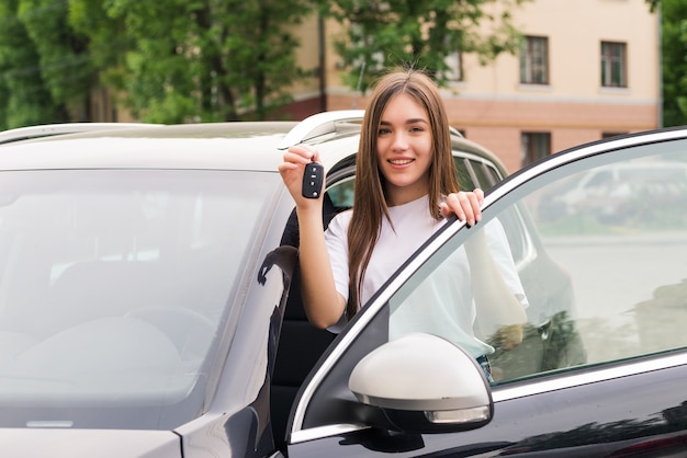 新しい車のキーと幸せな若い笑顔の女性