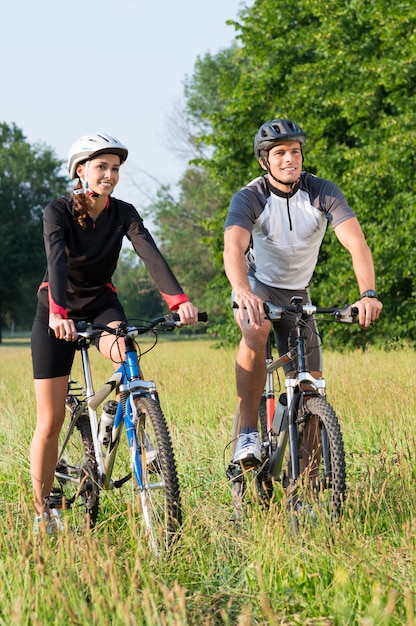 Happy young sportive man and woman on bicycle