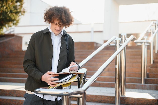 晴れた日に本を読んで勉強し、とても笑顔の幸せな若い学生の男の子