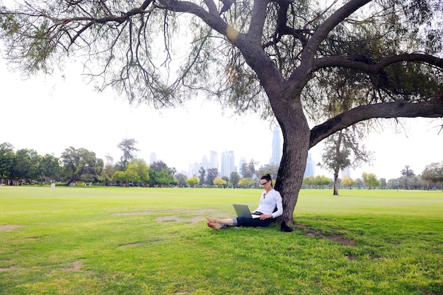 happy young student woman with laptop in city park study