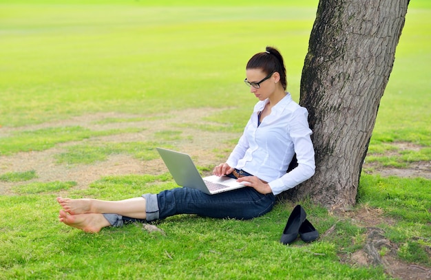 happy young student woman with laptop in city park study